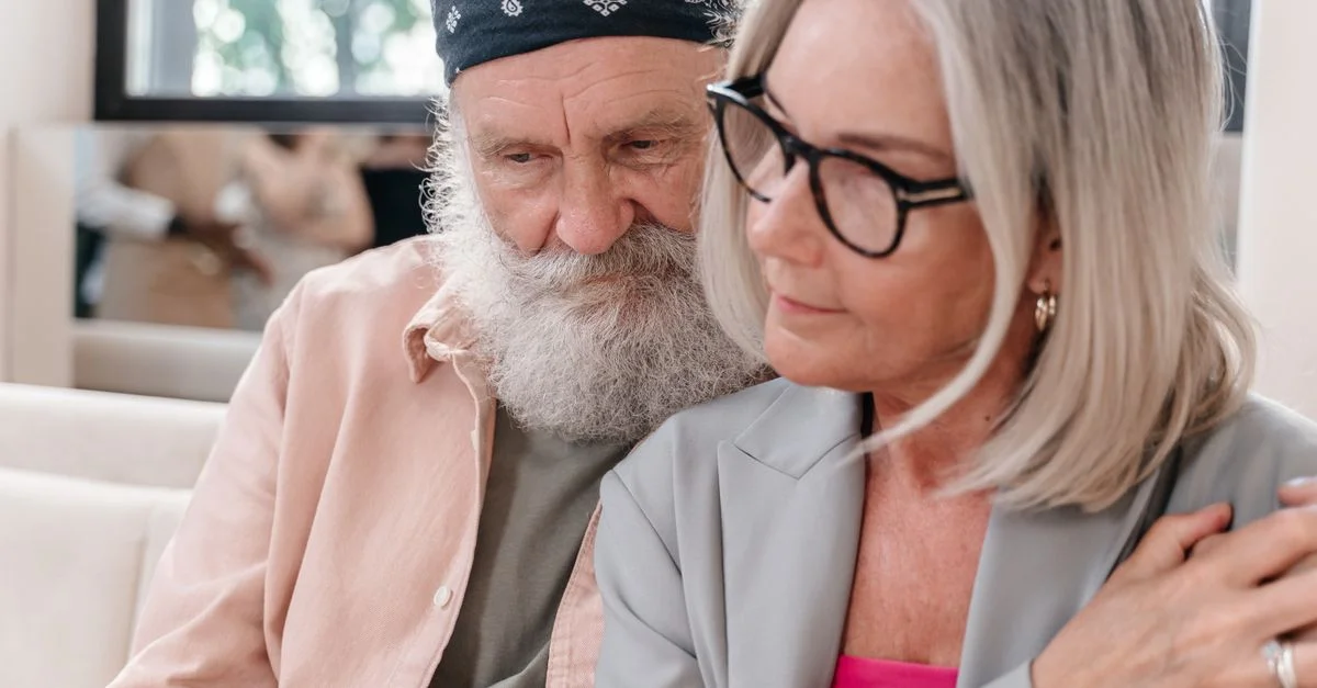 Couple senior portant des lunettes et un bandana, partageant un moment ensemble à l'intérieur.